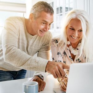 couple pleased with savings looking at laptop