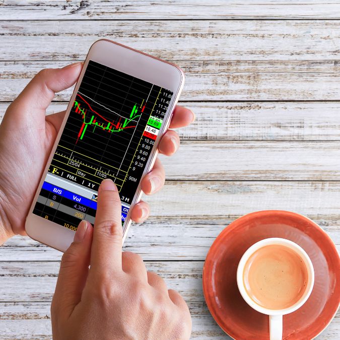 trading forex on phone with cup of tea